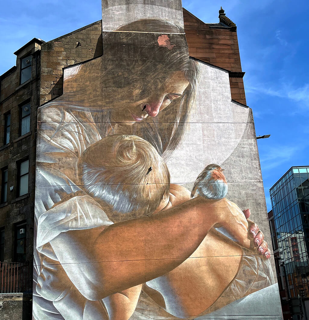 A street art mural of St Enoch cradling her beloved St Mungo