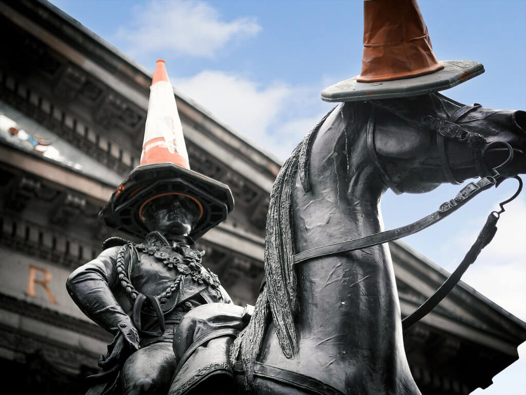 A bronze statue of the Duke of Wellington on his horse, both of them have traffic cones for hats