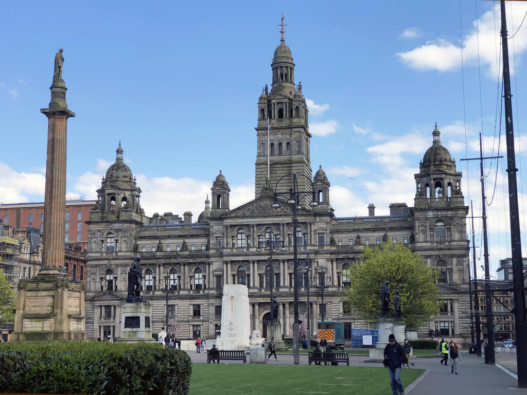 A statue of Sir Walter Scott up high in George Square, with City Chambers in the background